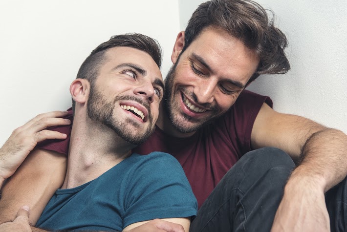 Happy gay couple embraced, joking and having fun in an intimate hug